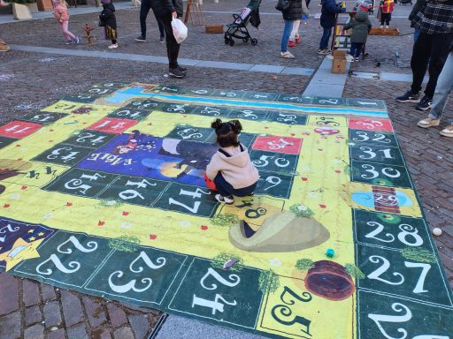 tappeto ludico Bambina gioca su un grande gioco da tavolo colorato all'aperto.